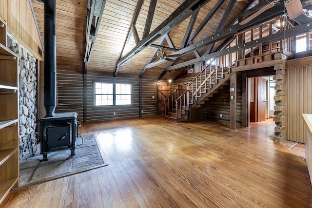 unfurnished living room with stairs, wood ceiling, a wood stove, and hardwood / wood-style flooring