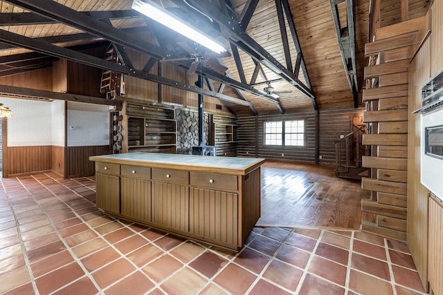 kitchen featuring tile countertops, lofted ceiling with beams, wooden ceiling, tile patterned flooring, and wooden walls