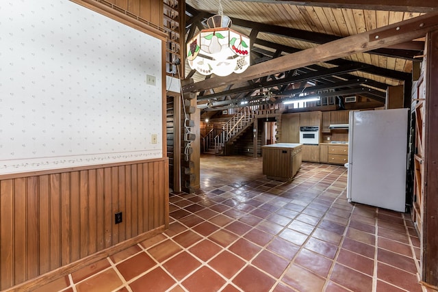 kitchen with a wainscoted wall, vaulted ceiling with beams, wooden ceiling, wooden walls, and white appliances