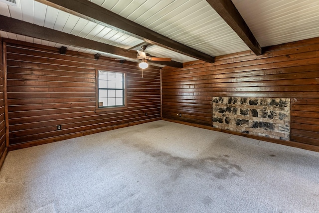 carpeted empty room featuring visible vents, ceiling fan, wood walls, and beam ceiling