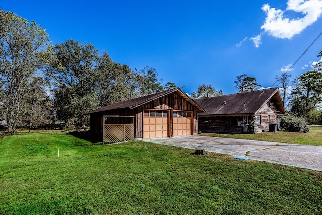 exterior space featuring driveway, an outbuilding, and a yard