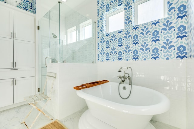 full bathroom with a stall shower, marble finish floor, a soaking tub, and tile walls