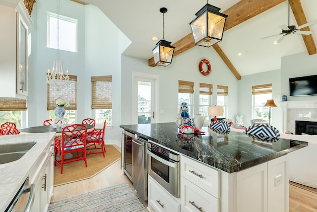 kitchen with dark stone counters, dishwasher, open floor plan, light wood-type flooring, and beam ceiling