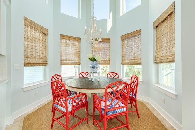 dining space with a chandelier, a high ceiling, wood finished floors, and baseboards