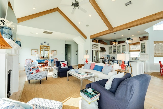 living area with a fireplace, visible vents, and beamed ceiling