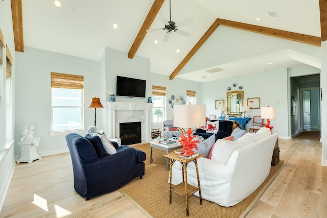 living area featuring light wood-style flooring, beamed ceiling, plenty of natural light, and a high end fireplace