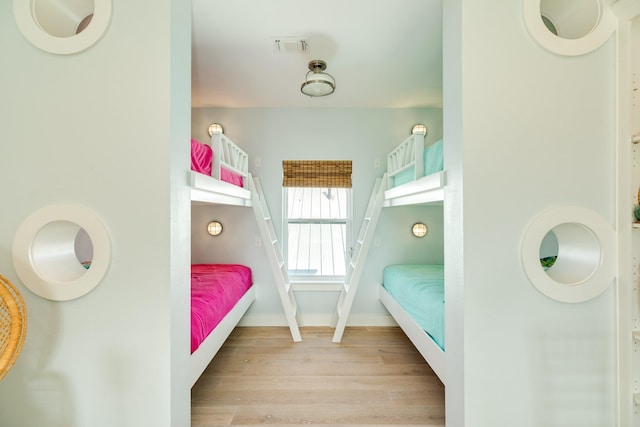 bedroom featuring light wood-type flooring, visible vents, and baseboards