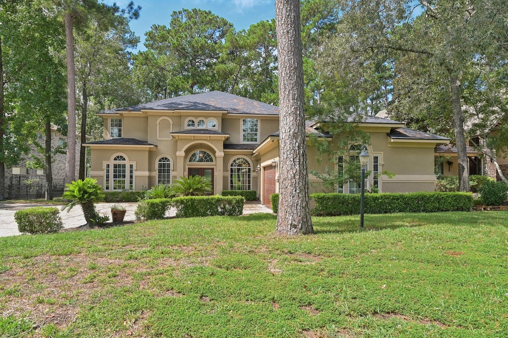 mediterranean / spanish-style house featuring a front yard, an attached garage, and stucco siding