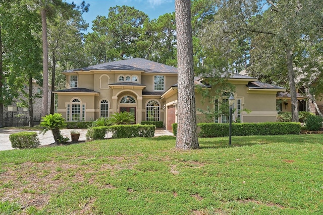 mediterranean / spanish-style house featuring a front yard, an attached garage, and stucco siding