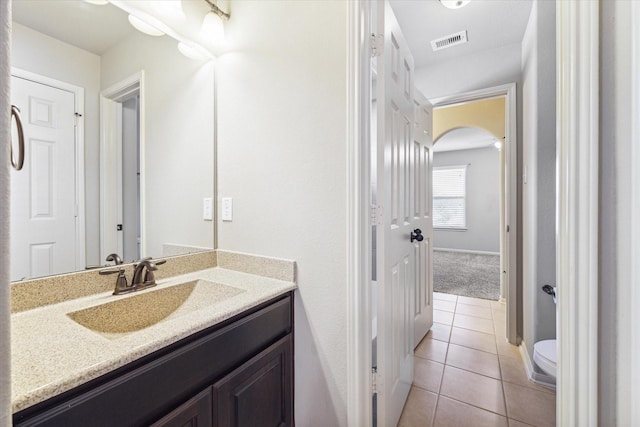 half bath with visible vents, toilet, vanity, and tile patterned flooring