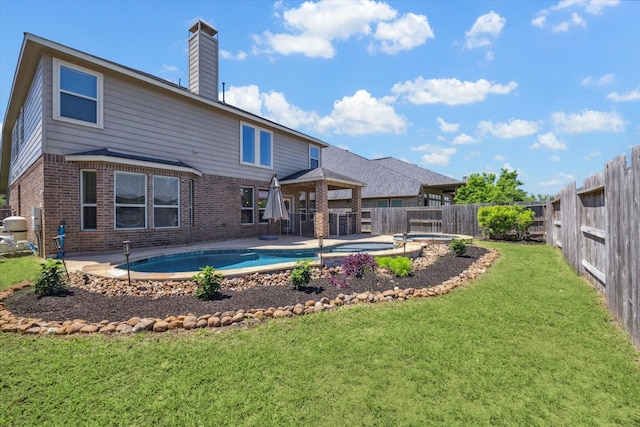 back of property with brick siding, a lawn, a chimney, and a fenced backyard