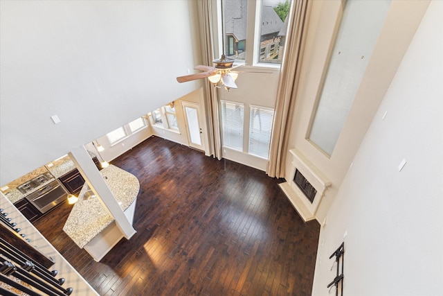 unfurnished living room with a fireplace, a high ceiling, ceiling fan, and hardwood / wood-style flooring