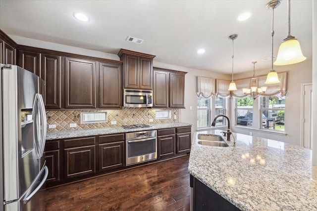 kitchen featuring visible vents, dark wood-type flooring, a sink, stainless steel appliances, and decorative backsplash