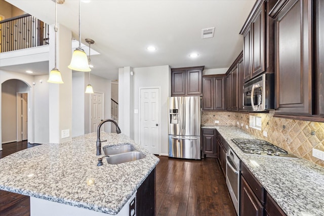 kitchen with visible vents, a sink, dark wood-style floors, stainless steel appliances, and dark brown cabinetry