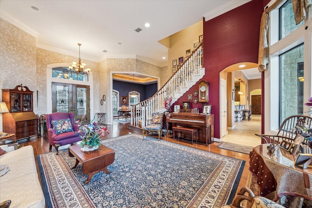 living area featuring stairway, arched walkways, wood finished floors, and ornamental molding