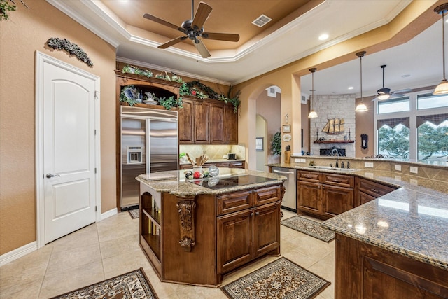 kitchen with arched walkways, open shelves, appliances with stainless steel finishes, and a raised ceiling