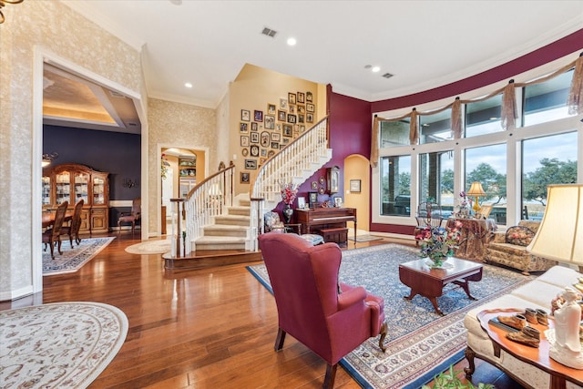 living room featuring visible vents, arched walkways, stairway, ornamental molding, and hardwood / wood-style floors