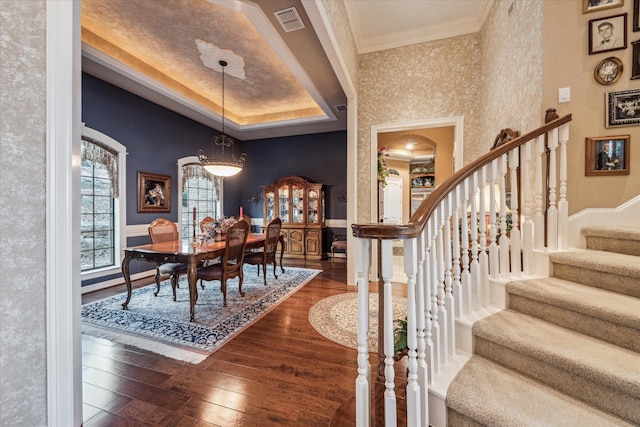 dining area with ornamental molding, a tray ceiling, visible vents, and dark wood finished floors