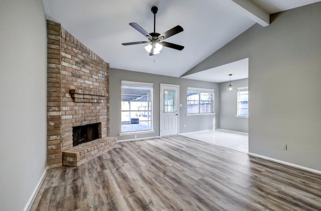 unfurnished living room with wood finished floors, baseboards, vaulted ceiling with beams, ceiling fan, and a brick fireplace