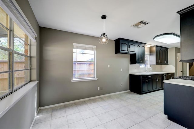 kitchen with visible vents, baseboards, light countertops, hanging light fixtures, and a sink