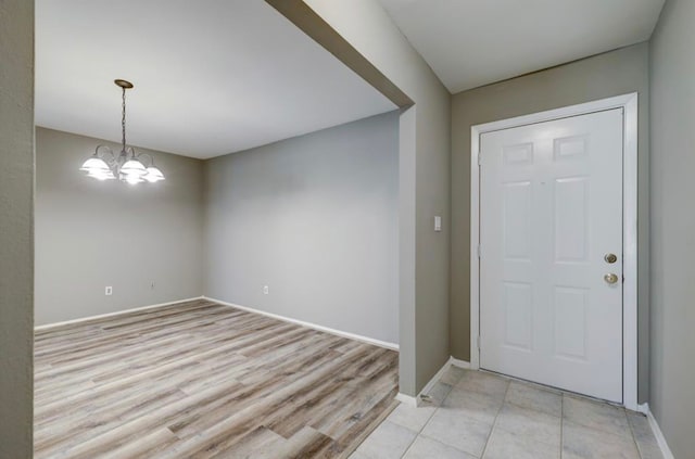 foyer with an inviting chandelier, light wood-style flooring, and baseboards