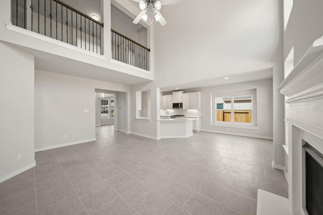 unfurnished living room featuring plenty of natural light, a fireplace, baseboards, and ceiling fan