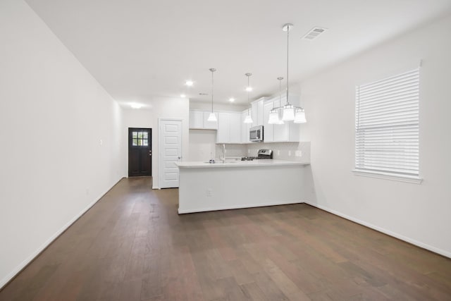 18823 Cypress Meadow Ct, Magnolia, TX 77355 - kitchen featuring a peninsula, stainless steel appliances, visible vents, dark wood-style flooring, and light countertops