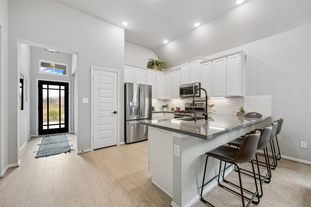 18823 Cypress Meadow Ct, Magnolia, TX 77355 - kitchen featuring appliances with stainless steel finishes, a peninsula, high vaulted ceiling, backsplash, and white cabinets