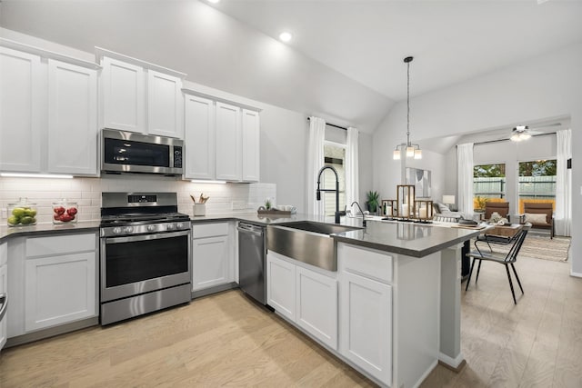18823 Cypress Meadow Ct, Magnolia, TX 77355 - kitchen featuring stainless steel appliances, a peninsula, vaulted ceiling, dark countertops, and tasteful backsplash