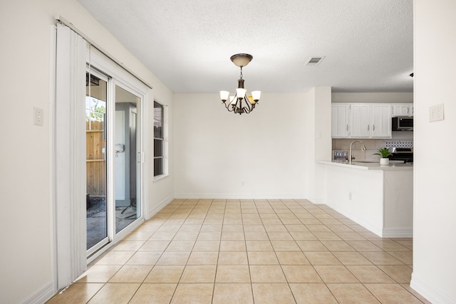 interior space featuring light tile patterned floors, visible vents, an inviting chandelier, a textured ceiling, and baseboards