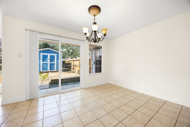 empty room featuring light tile patterned floors, a textured ceiling, baseboards, and an inviting chandelier