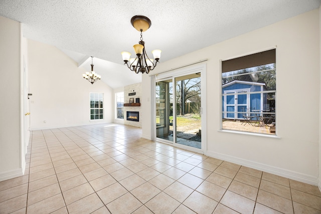 unfurnished living room featuring lofted ceiling, a textured ceiling, tile patterned flooring, a notable chandelier, and a fireplace