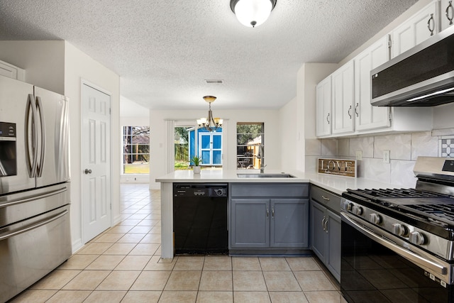 kitchen featuring light tile patterned floors, stainless steel appliances, white cabinets, a sink, and a peninsula