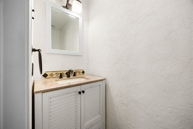 bathroom featuring a textured wall, vanity, and decorative backsplash