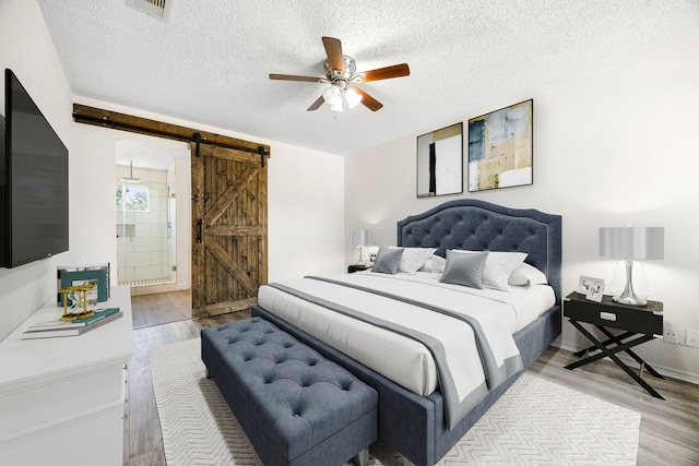 bedroom featuring a barn door, baseboards, ceiling fan, wood finished floors, and a textured ceiling