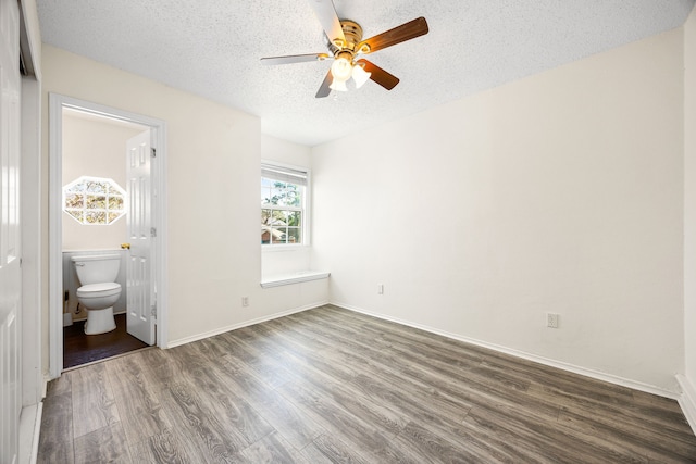 unfurnished bedroom featuring ceiling fan, connected bathroom, a textured ceiling, wood finished floors, and baseboards