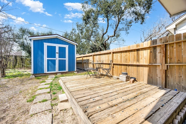 deck with a storage shed, an outbuilding, and a fenced backyard