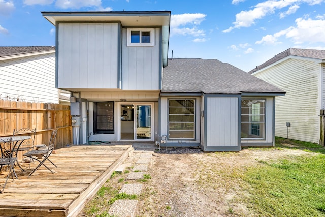 rear view of property featuring a shingled roof, fence, and a deck