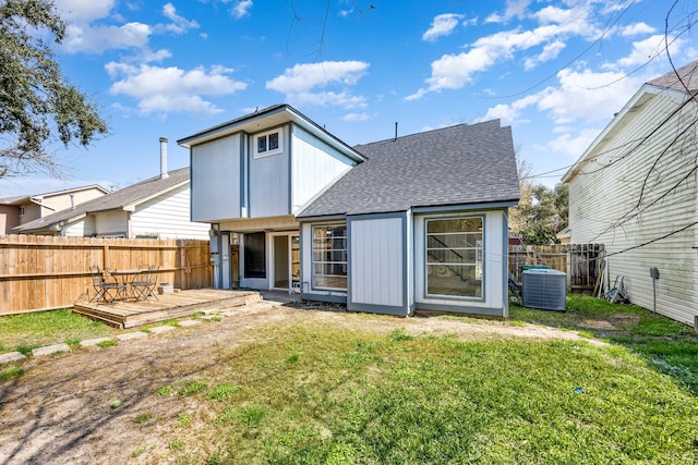 back of property with a deck, a fenced backyard, central air condition unit, a shingled roof, and a lawn