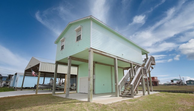 back of property featuring a garage, a carport, stairs, and a lawn