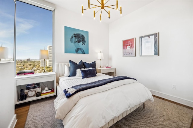 bedroom featuring an inviting chandelier, baseboards, and wood finished floors