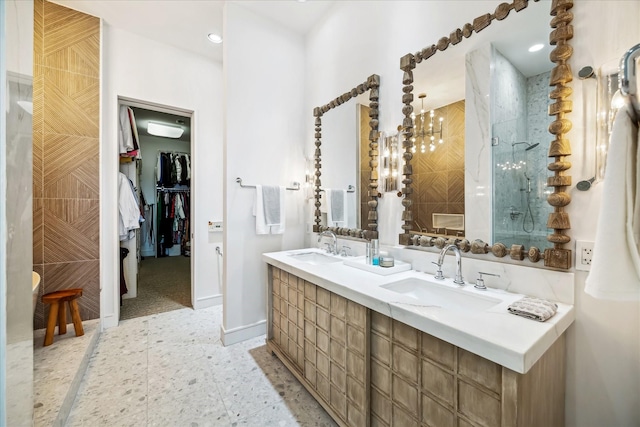 full bathroom with a tile shower, double vanity, a sink, and a walk in closet