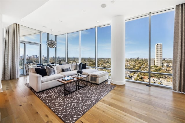 living room featuring a wealth of natural light, floor to ceiling windows, a city view, and hardwood / wood-style flooring