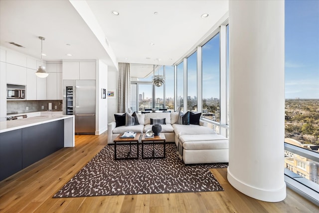 living area with expansive windows, light wood-type flooring, baseboards, and recessed lighting