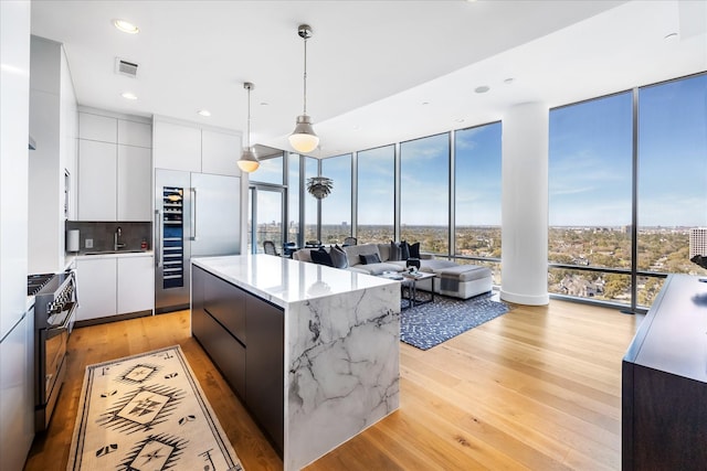 kitchen featuring white cabinets, modern cabinets, visible vents, and a wall of windows