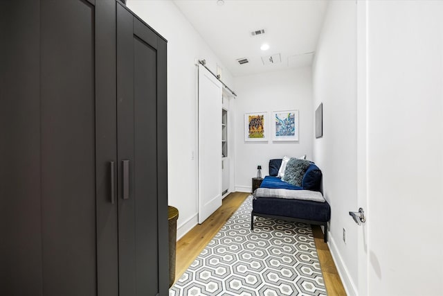 hall with light wood-type flooring, visible vents, and baseboards