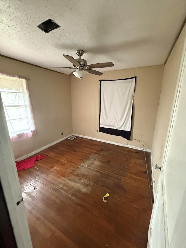 unfurnished bedroom with wood-type flooring, ceiling fan, a textured ceiling, and baseboards