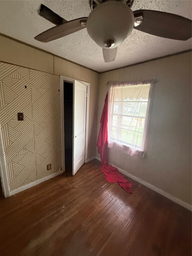 unfurnished bedroom featuring ceiling fan, a textured ceiling, ornamental molding, and hardwood / wood-style floors