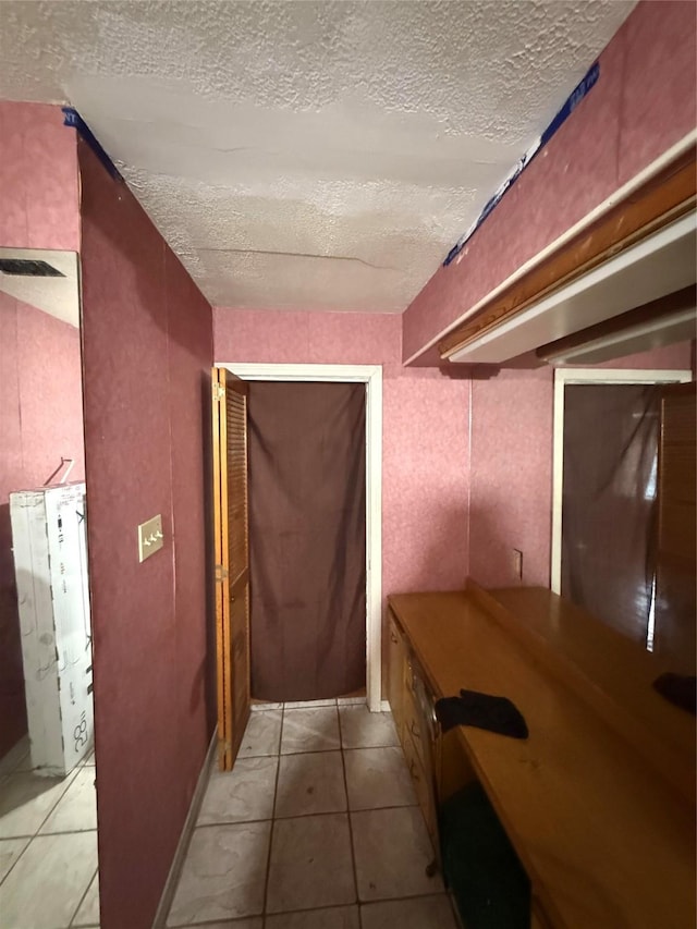 corridor with light tile patterned floors and a textured ceiling