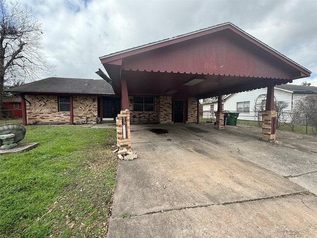 view of front of house with brick siding, fence, concrete driveway, a carport, and a front lawn